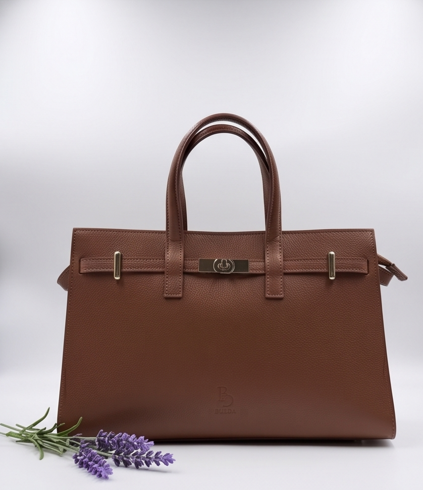Front view of a brown leather satchel bag with a top handle and gold hardware against a clean white background.