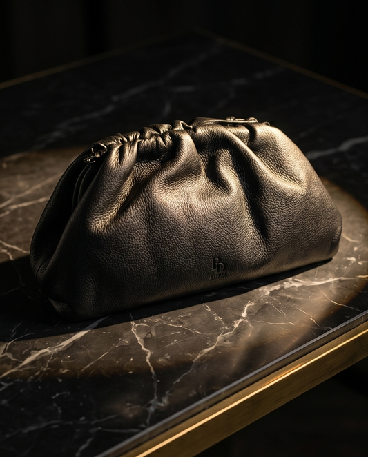 Sophisticated black natural nappa leather pouch clutch on a dark veined marble surface, Italian luxury design.