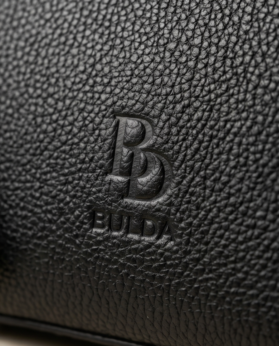 Macro shot of embossed Bulda logo on high-quality black leather grain.