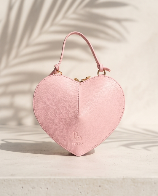 Front view of the Bulda heart-shaped leather handbag in pink featuring a top handle and embossed logo.