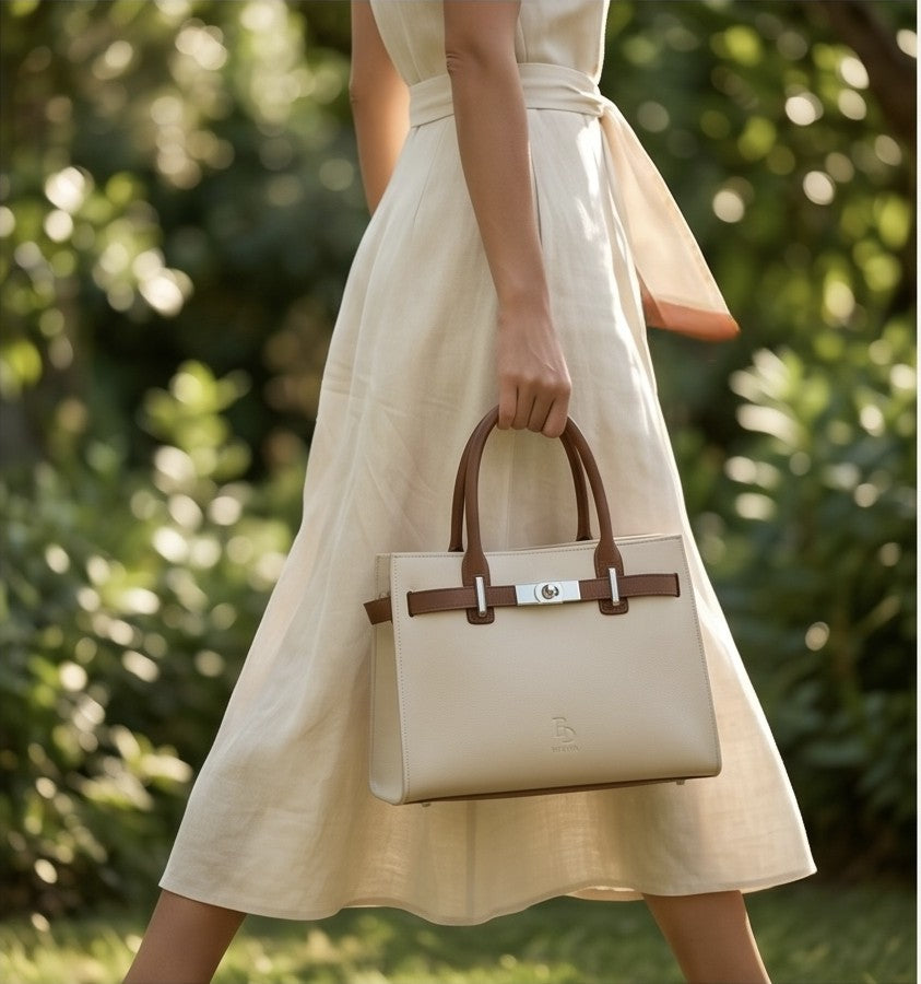 Lifestyle shot of a woman holding the luxury tote bag while walking in a garden.
